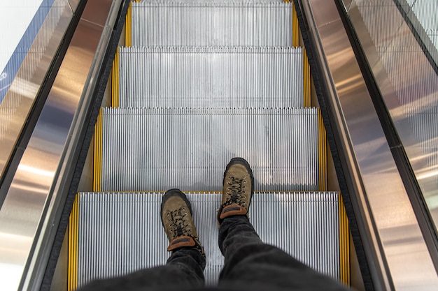 Male feet on the escalator, top view.