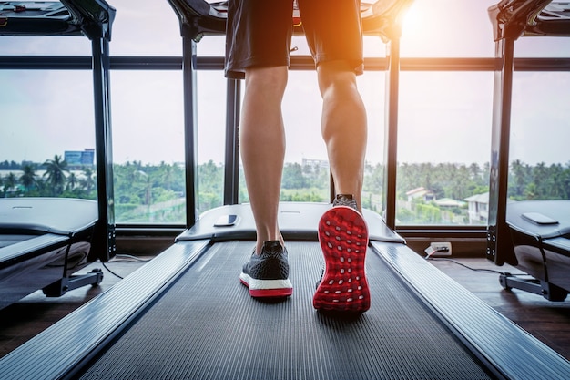 Мужские ноги в кроссовках на беговой дорожке в тренажерном зале. Концепция упражнений.