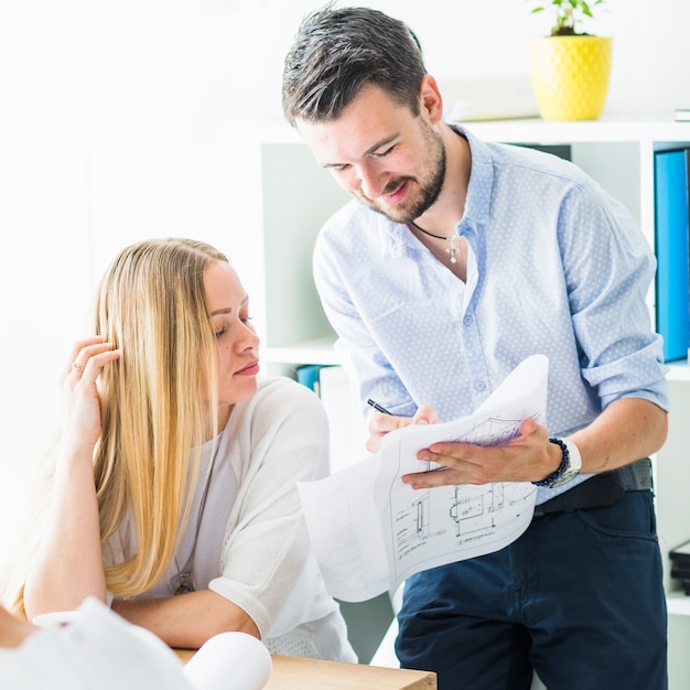 Male and female architect working on blueprint