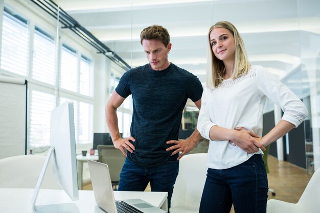 Male and female business executives standing with hands on hips