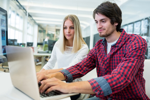 Male and female business executives working on laptop