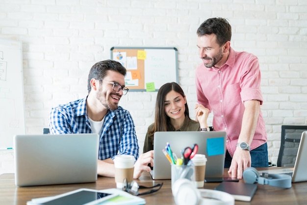 Male and female business people communicating over laptop in meeting at workplace