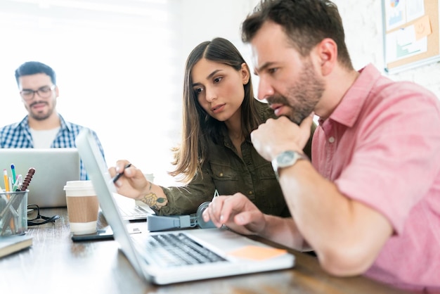 Male and female colleagues planning strategy over laptop at office desk