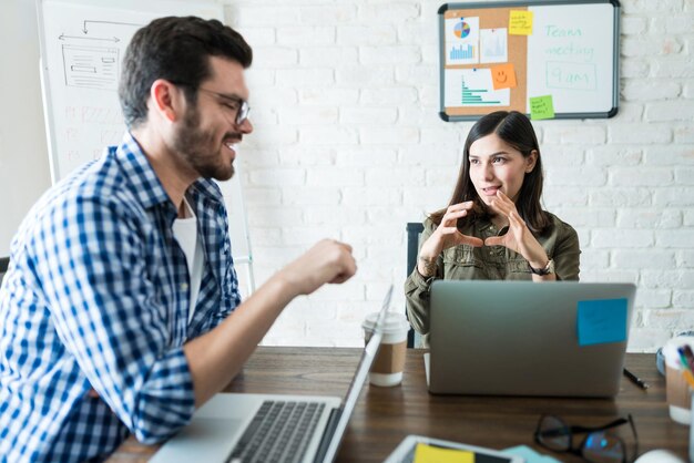 Male and female colleagues sharing ideas while using laptop at office