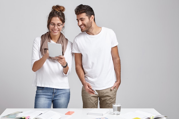 Male and female designers or scientific workers stand near workplace in cozy office.