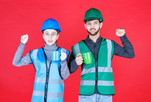 Инженеры мужского и женского пола со шлемом, держащим синие и зеленые кружки и показывающим знак удовлетворения.