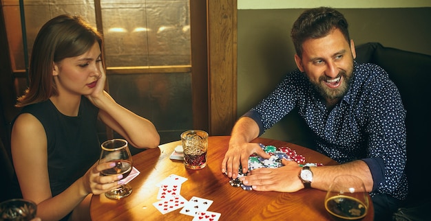 Male and female friends sitting at wooden table.