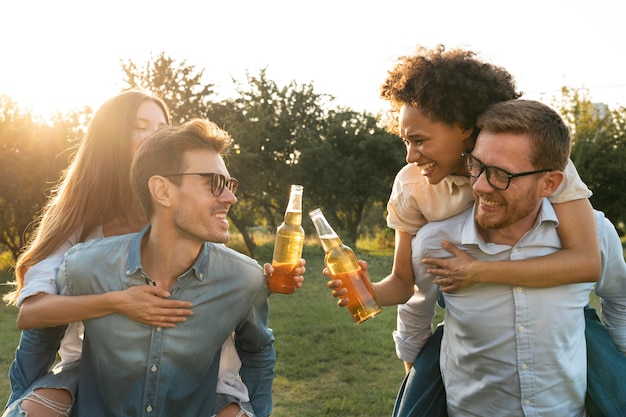 Друзья мужского и женского пола проводят время вместе на открытом воздухе и пьют пиво