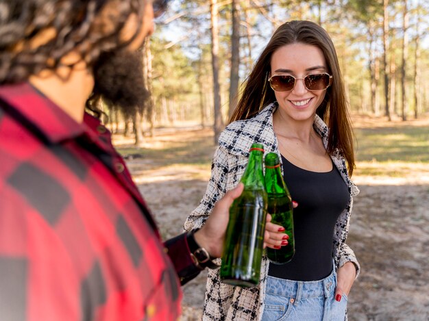 Male and female friends toasting with beer over barbecue outdoors