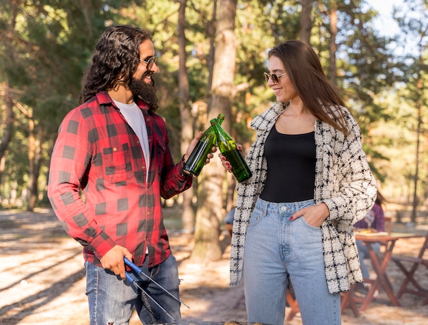 Male and female friends toasting with beer over barbecue