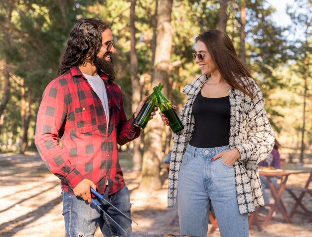 Male and female friends toasting with beer over barbecue