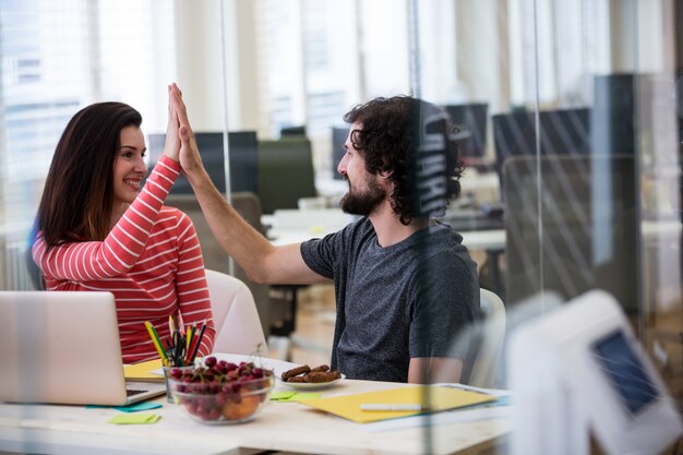Male and female graphic designers giving high five to each other