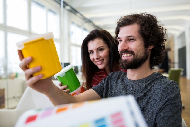 Male and female graphic designers holding plastic container