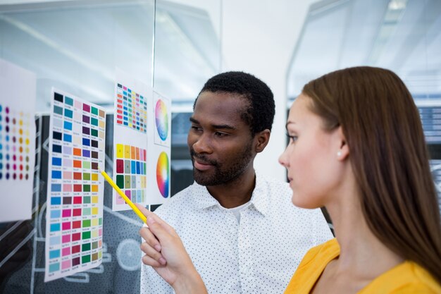 Male and female graphic designers interacting over color chart