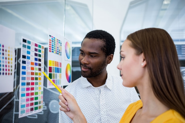 Male and female graphic designers interacting over color chart