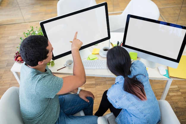 Male and female graphic designers interacting over computer