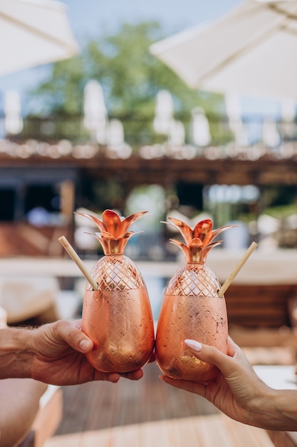 Free photo male and female hands holding cocktails by the pool