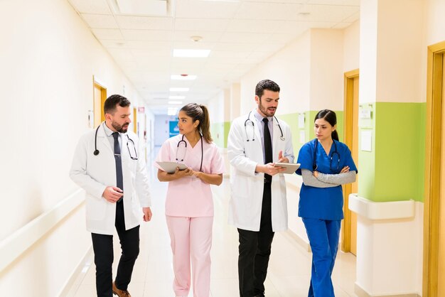 Male and female Hispanic healthcare workers discussing reports while walking in corridor at hospital