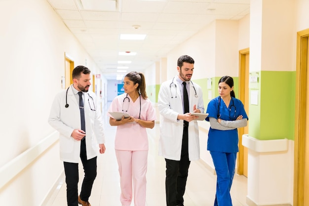 Male and female Hispanic healthcare workers discussing reports while walking in corridor at hospital