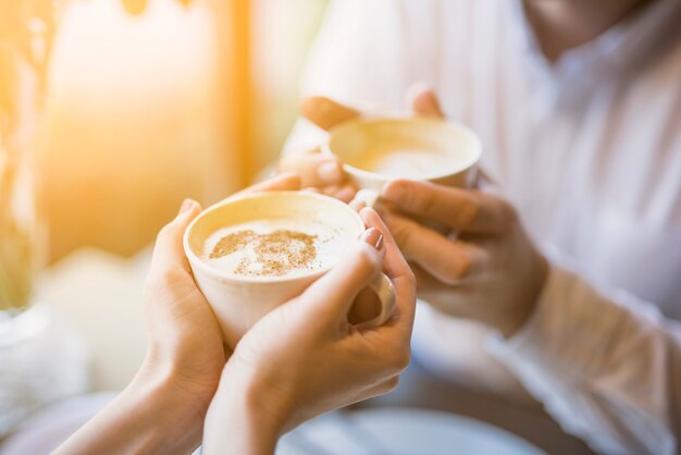 Male and female holding cups of hot drink 