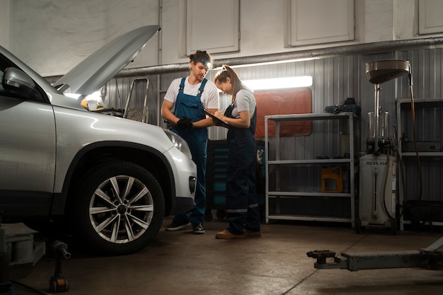 Male and female mechanics working in the shop on a car