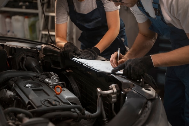 Foto gratuita meccanici maschili e femminili che lavorano nel negozio su un'auto