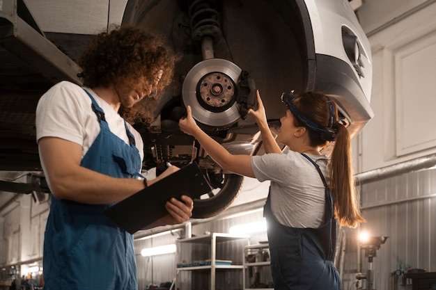 Male and female mechanics working in the shop on a car