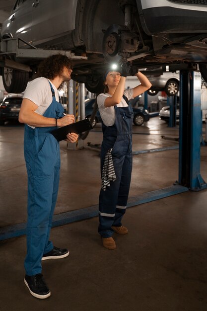 Male and female mechanics working in the shop on a car