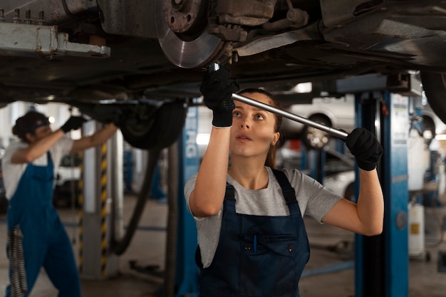 Foto gratuita meccanici maschili e femminili che lavorano nel negozio su un'auto