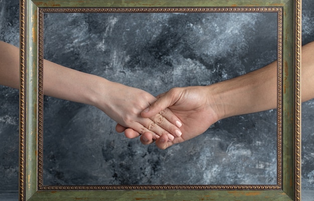Foto gratuita maschio e femmina si stringono la mano al centro della cornice.