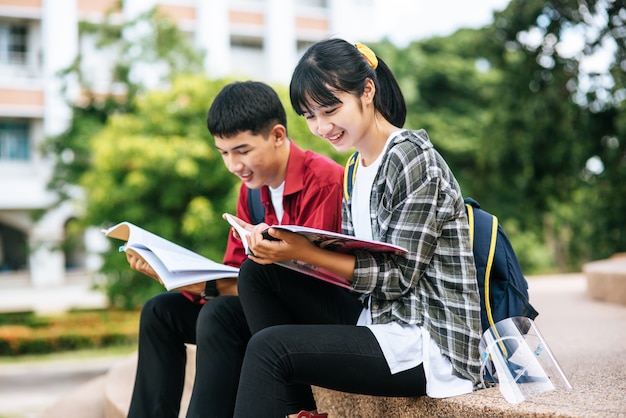 Male and female students sitting and reading books on the stairs.