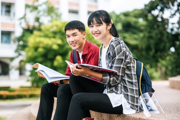 階段に座って本を読む男性と女性の学生。