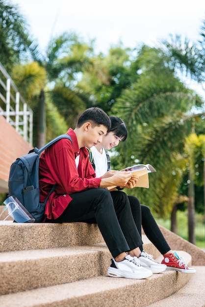 階段に座って本を読む男性と女性の学生。