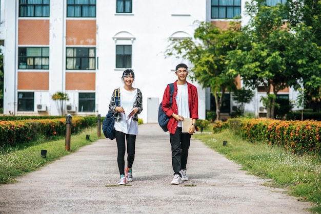 男性と女性の学生は顔を冷やし、大学の前に立っています。