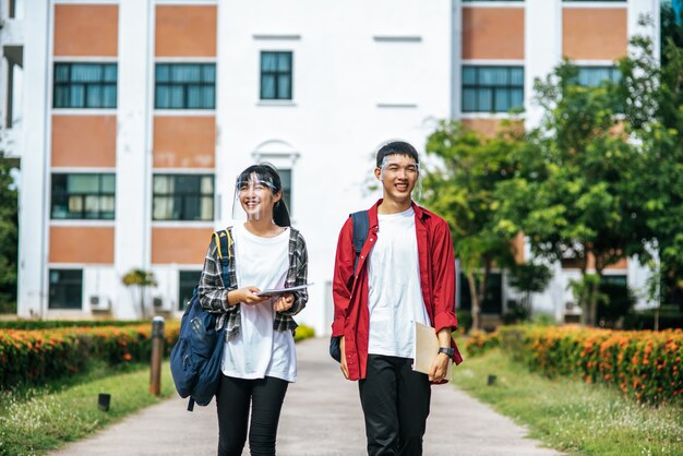 男性と女性の学生は顔を冷やし、大学の前に立っています。