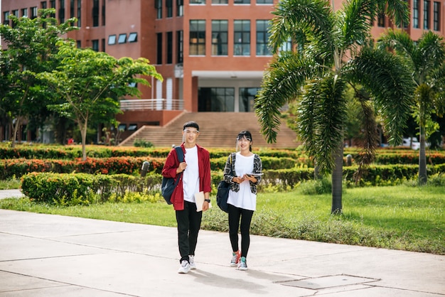男性と女性の学生は顔を冷やし、大学の前に立っています。