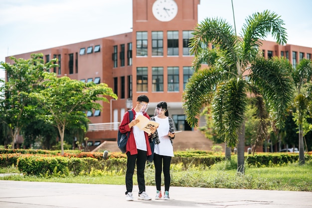 Le studentesse e gli uomini indossano il viso chill e sono in piedi di fronte all'università.