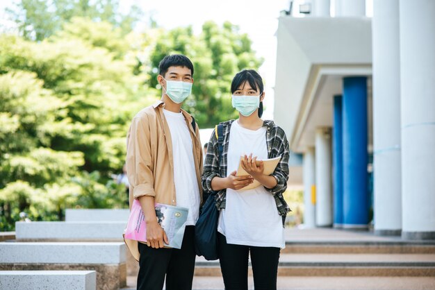 男性と女性の学生は、健康マスクを着用し、階段で互いに話します。