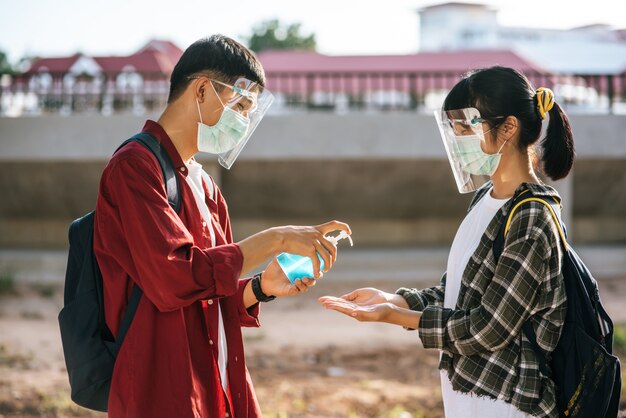 Male and female students wear masks and squeeze the gel to wash their hands.