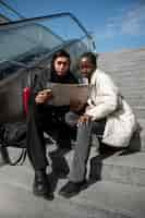 Free photo male and female tourists checking map while sitting on stairs