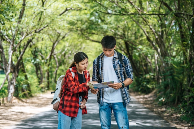 Male and female tourists look at the map on the road.