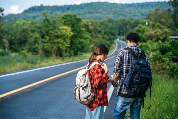 Male and female tourists look at the map on the road.