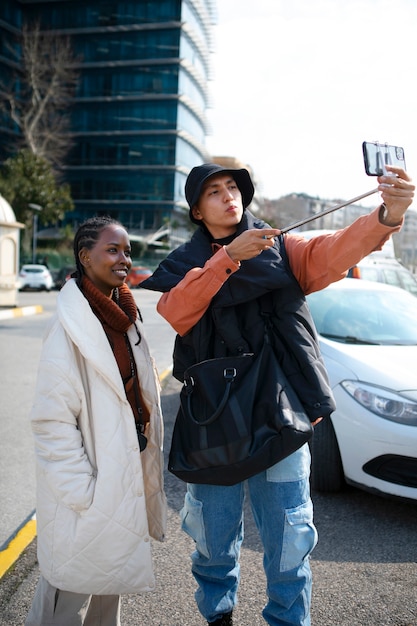 Free photo male and female tourists taking selfie with stick outside