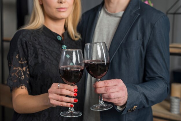 Male and female with glasses of wine in room