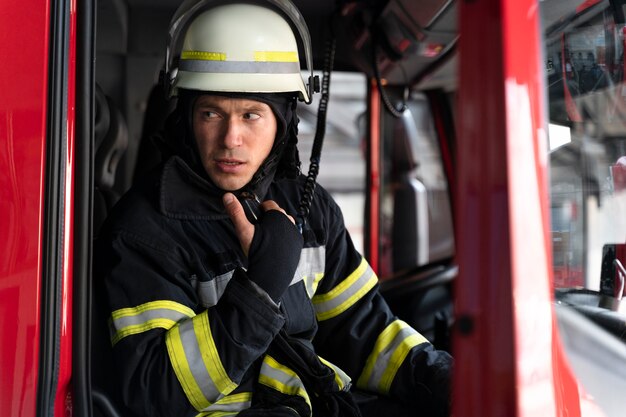 Male firefighter in fire truck using radio station