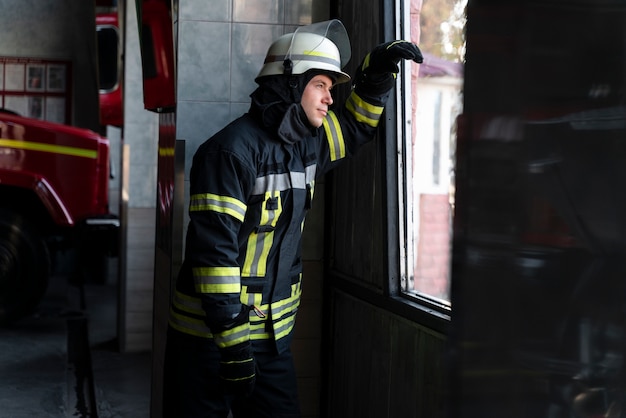 Male firefighter at station equipped with suit and safety helmet