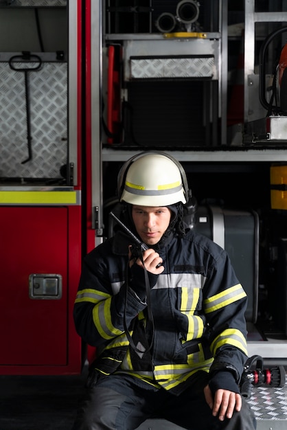 Foto gratuita vigile del fuoco maschio alla stazione dotato di tuta e casco di sicurezza