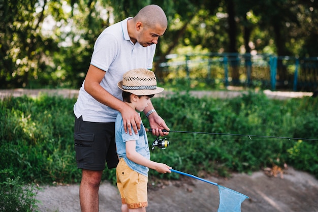 Free photo male fisherman assisting his son while fishing