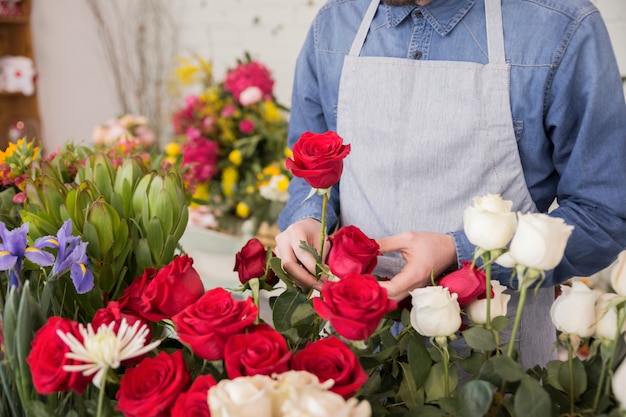 Мужской флорист расставляет свежие розы в цветочном магазине