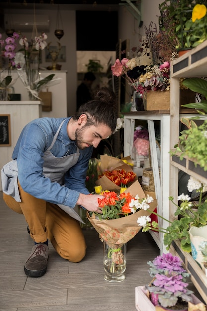 Male florist looking at beautiful red tulip bouquet in the shop